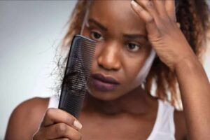 A woman looking at her shedding hair in a comb