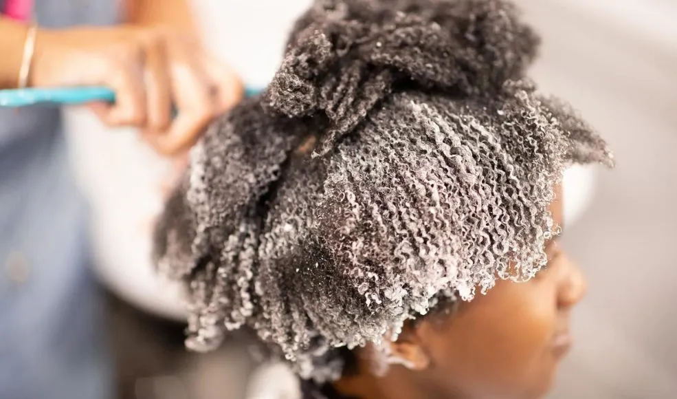 Conditioner being applied to sectioned afro hair during wash session