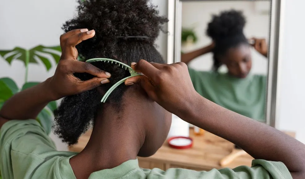 A black woman sectioning her hair with a green hair clip