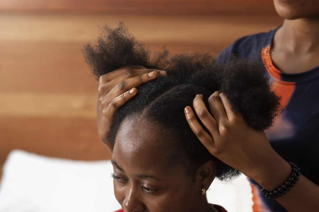 A woman with her parted down the middle and someone else holding both sides of the hair