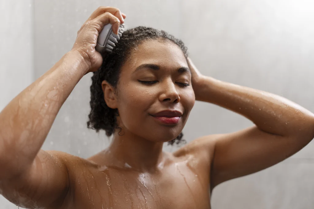 A woman washing her hair in a shower with her eyes closed