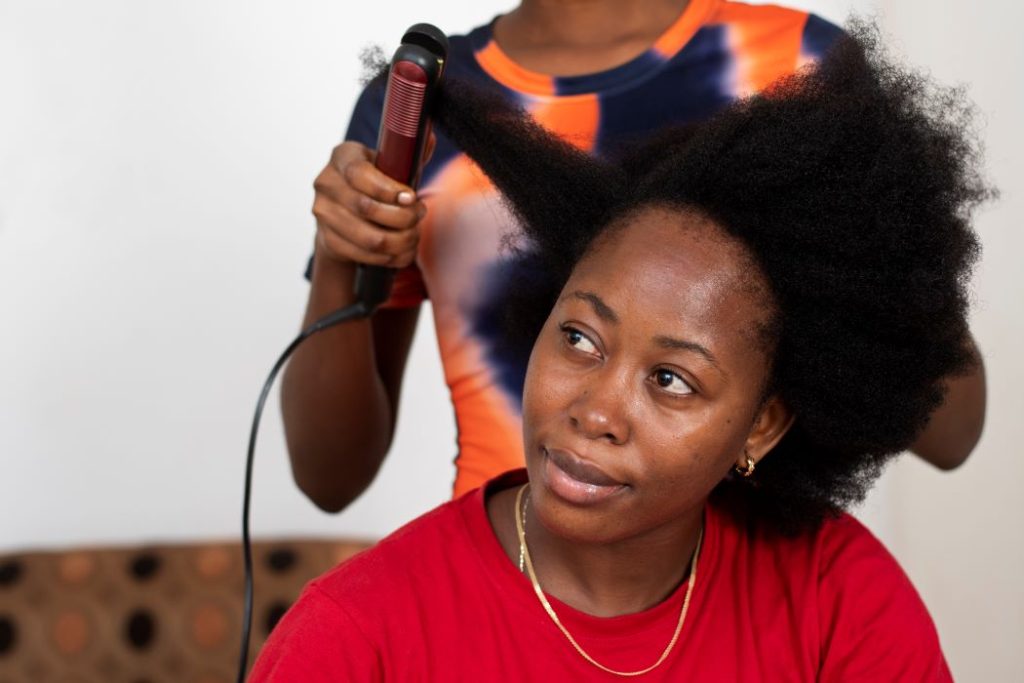 woman with 4c hair getting her hair straightened